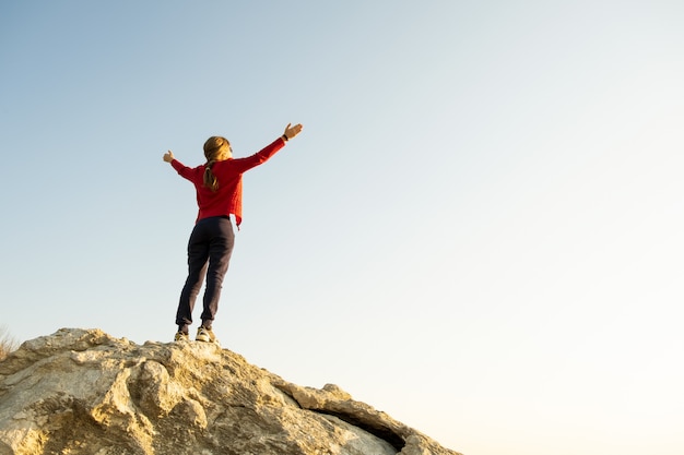 Woman hiker standing alone on big stone in mountains