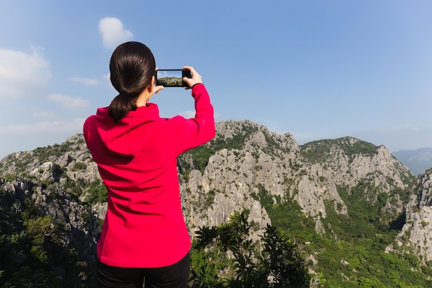 Woman hiker taking photo with cell phone