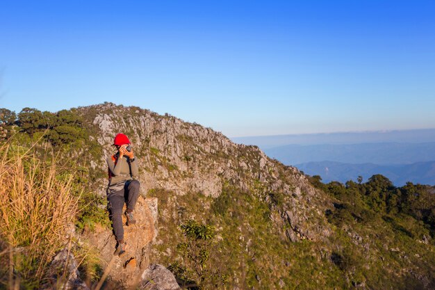 山にミラーレスカメラと写真を撮っている女性の登山人。バックパッカー写真の風景