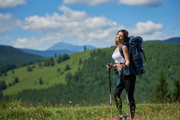 Viandante della donna con lo zaino che fa un'escursione in montagna