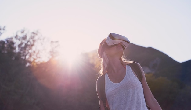 Woman hiking in a forest using a virtual reality headset to enhance the scenic nature Woman using a virtual reality headset to escape to the metaverse during a hike in a forest on holiday