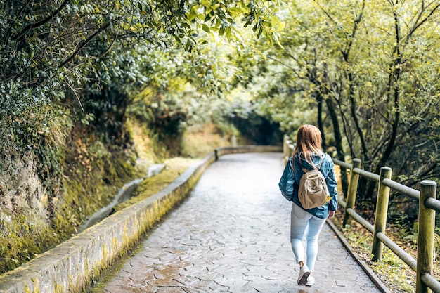 Foto donna che fa un'escursione su un sentiero tra gli alberi e con una ringhiera in legno