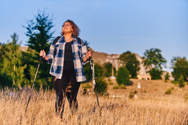 A woman hiking with a backpack and poles at sunset Selective focus