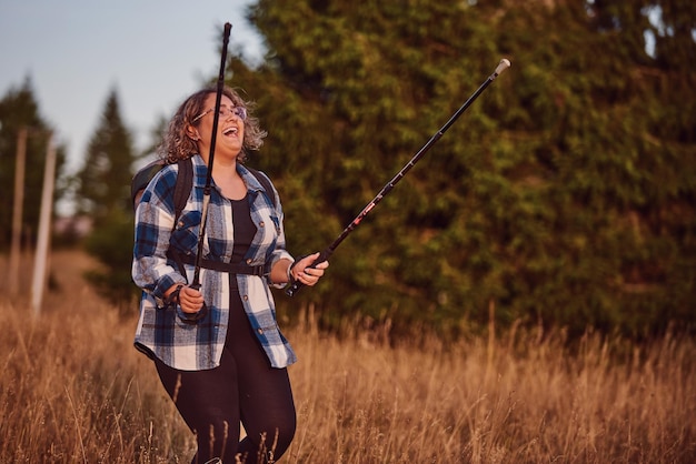 A woman hiking with a backpack and poles at sunset Selective focus