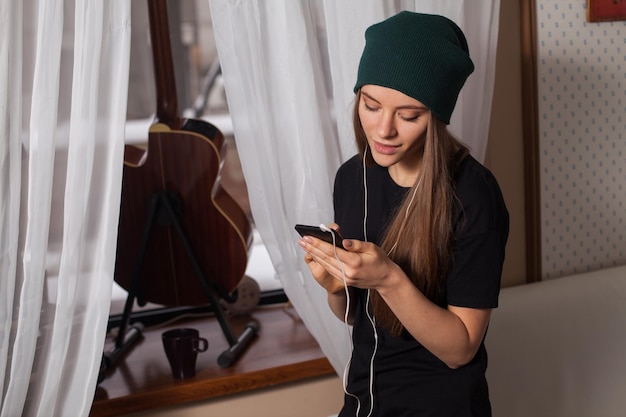 Pantaloni a vita bassa della donna in cappello verde che ascolta musica e si gode la vita