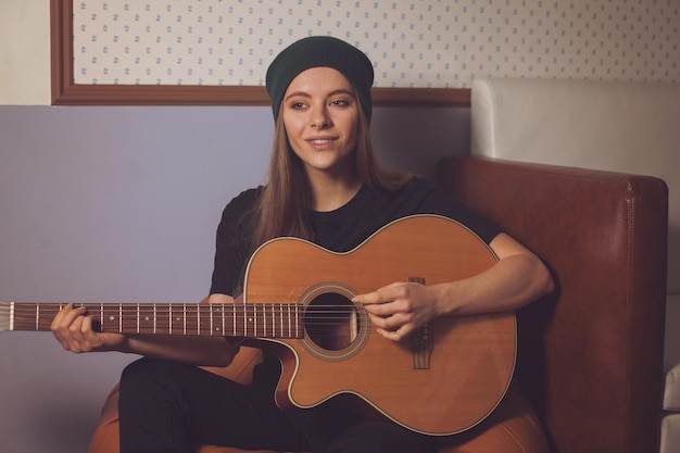 Woman hipster playing on guitar and enjoying music