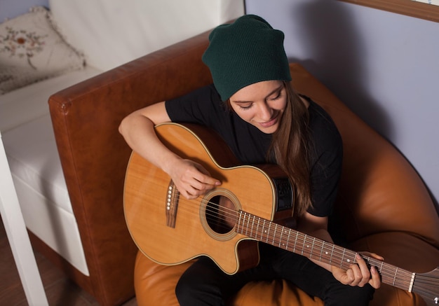 Woman hipster playing on guitar and singing