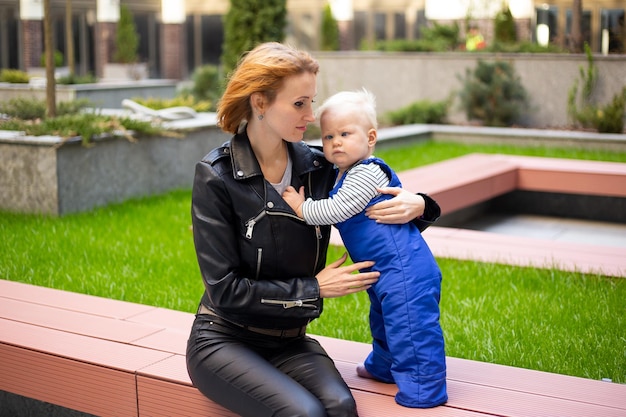 Woman hipster playing with child baby boy outdoors on urban background