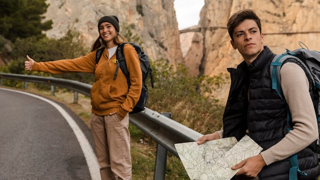 Photo woman hitch-hiking for a car and man holding map