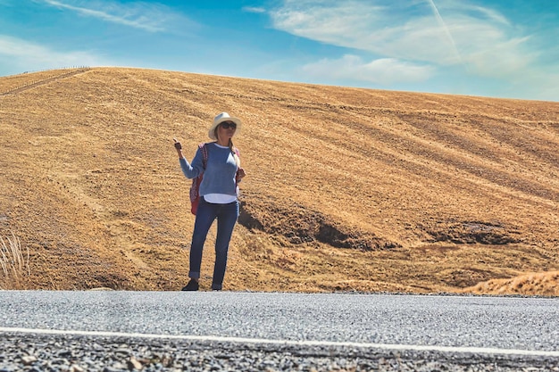 woman hitchhiking on road in forest hitchhiking with thumbs up in a countryside road Travelling