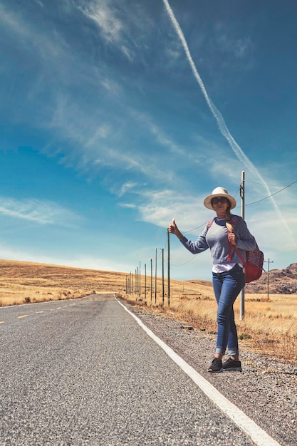 woman hitchhiking on road in forest hitchhiking with thumbs up in a countryside road Travelling