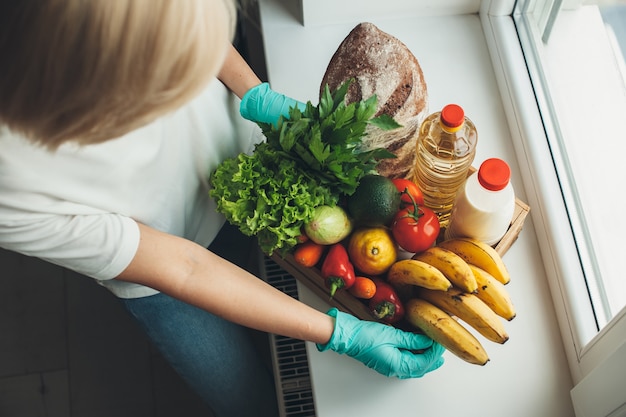 Foto donna che accumula frutta e verdura mentre indossa i guanti durante la quarantena