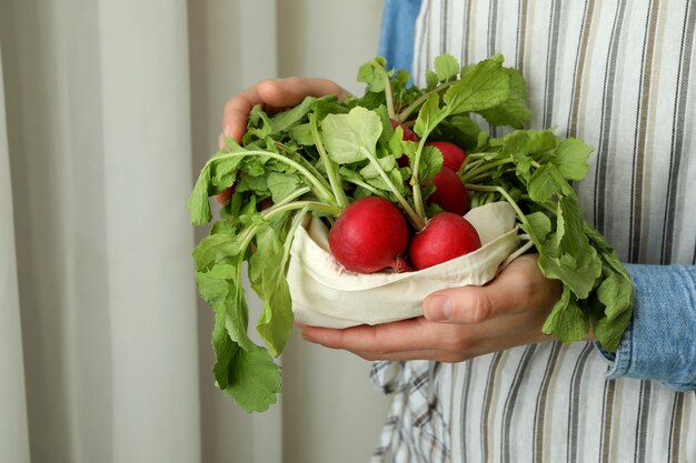 Woman hold bag with fresh radish, close up