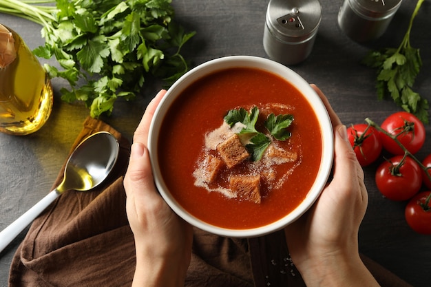 Woman hold bowl of tasty tomato soup, top view