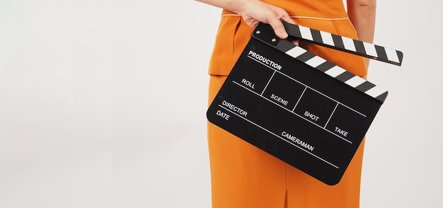 La donna tiene il clapper board e gira intornoindossa un abito giallo su sfondo biancoparte del corpo