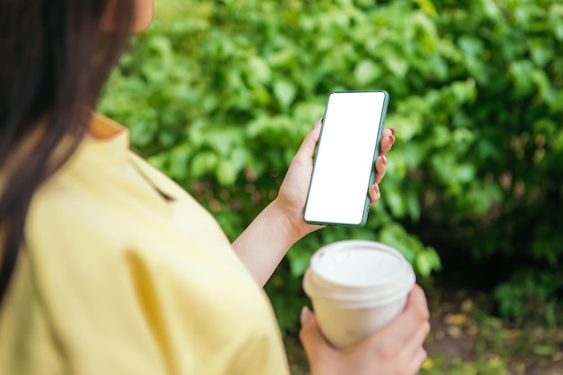 La donna tiene la tazza di caffè e il telefono all'esterno