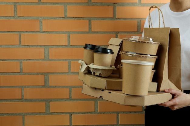 Photo woman hold delivery containers for takeaway food on brick wall