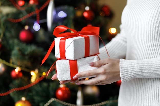 A woman hold a gifts New Year's decor Preparation for the holiday New Year's gifts on Christmas tree twigs Christmas tree Close up