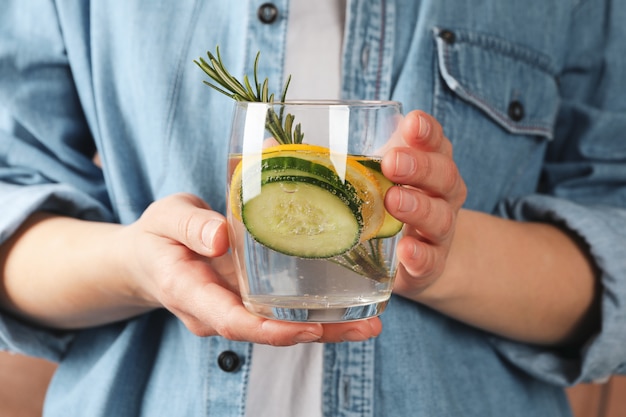 Woman hold glass with cucumber water, front view