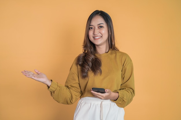 Woman hold a mobile phone with hand gesture presenting something