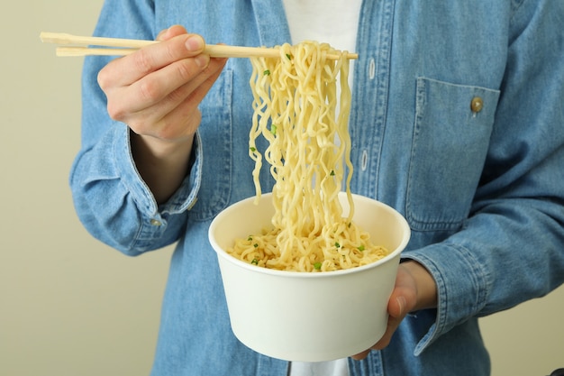 女性は、調理された麺で紙のボウルと箸を保持します