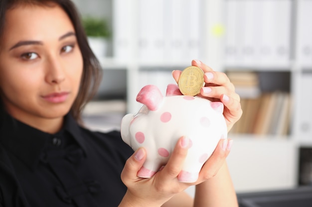 Woman hold piggybank in arms put money into moneybox