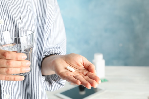 女性は錠剤と水のガラスを保持します