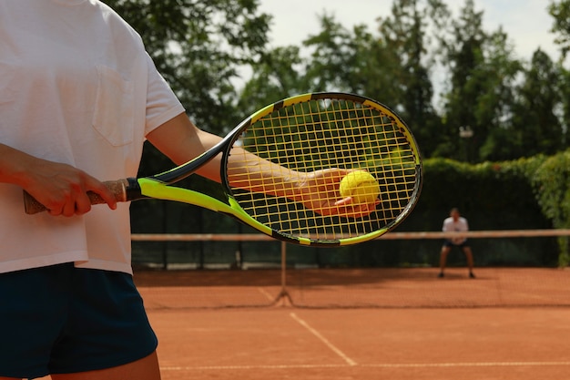 Woman hold racket and tennis ball on clay court