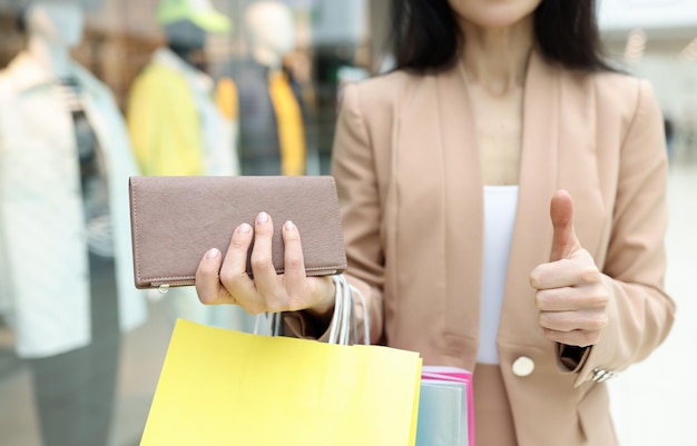 Woman hold wallet full with cash show thumbs up gesture with finger