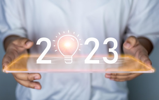 Woman holding 2023 icon and light bulb Represents the goal setting for 2023 .
