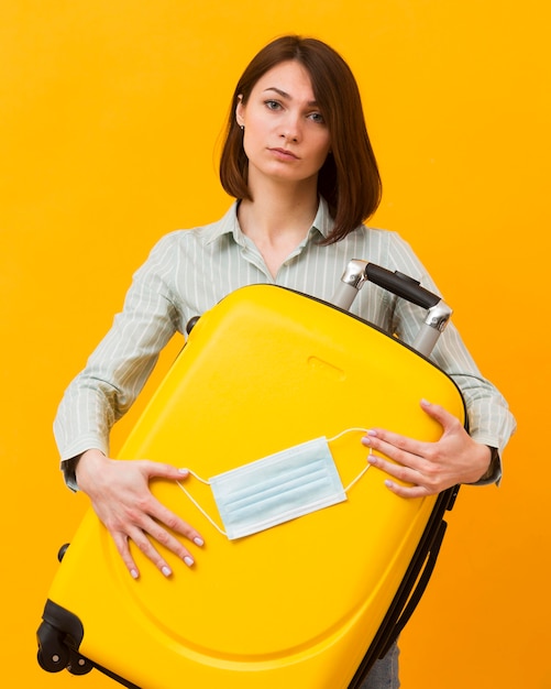 写真 黄色の荷物と医療マスクを保持している女性