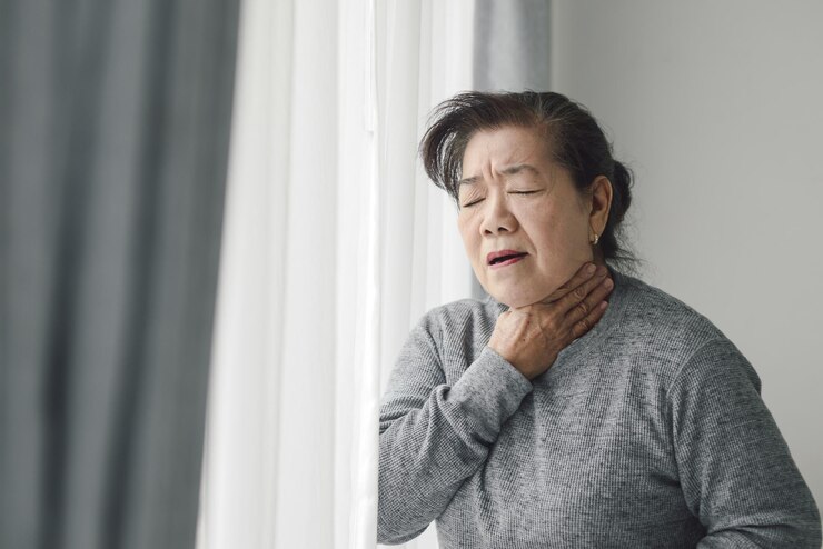 Photo 집 의 창문  에 서 있는 여자 가 목 을 아프게 들고 있다