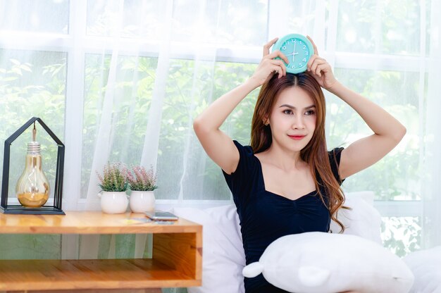 Woman holding an alarm clock in bed