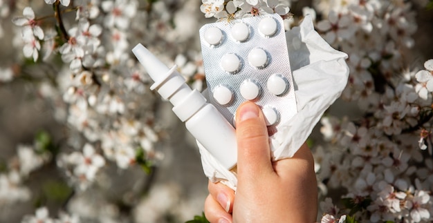 Woman holding allergy pills, drugs and nose spray against kind of an allergies during spring time, helathcare concept