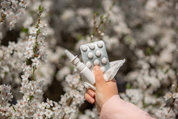 Woman holding allergy pills, drugs and nose spray against kind of an allergies during spring time, helathcare concept