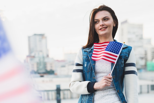 胸の近くにアメリカの国旗を保持している女性