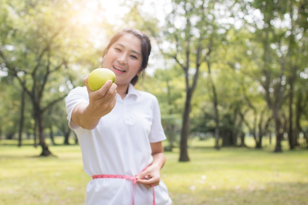 Woman holding apple and use waist line, diet and healthy body concept