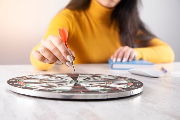 Woman holding arrow in the target on table