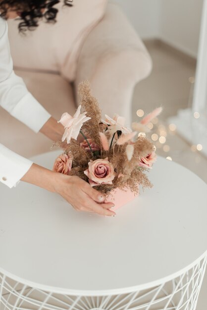 ピンクのボックスに人工的なミニマルな花を保持している女性