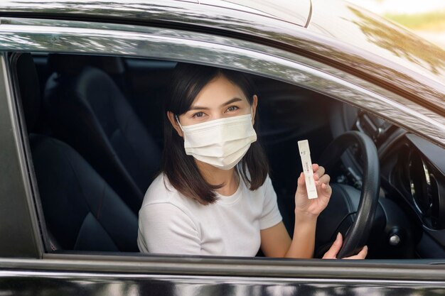 A woman holding atk in car do a selfcollection test for a COVID19 test health and safety