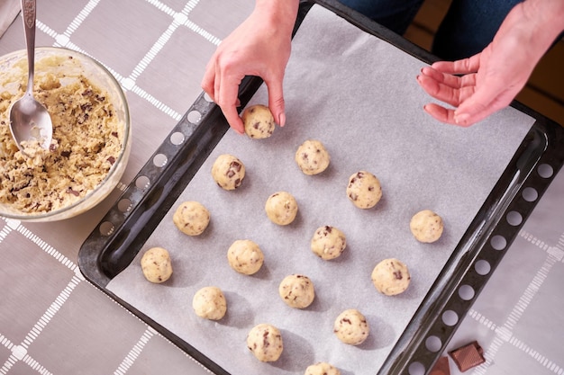 Woman holding ball of raw dough while making Chocolate chip cookies