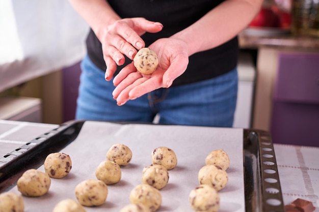 Woman holding ball of raw dough while making Chocolate chip cookies