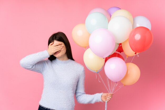 Woman holding balloons over isolated wall