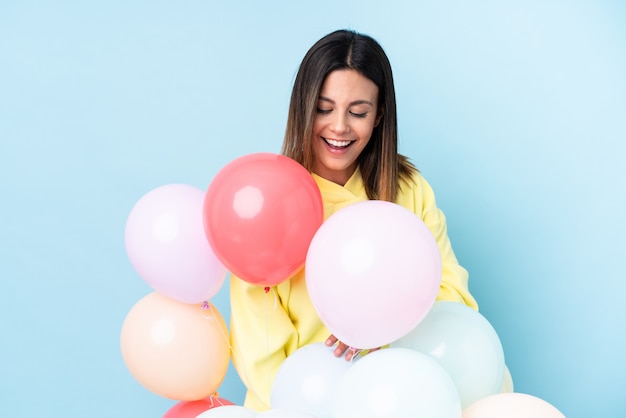 Woman holding balloons in a party over blue wall