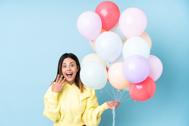 Woman holding balloons in a party with surprise facial expression