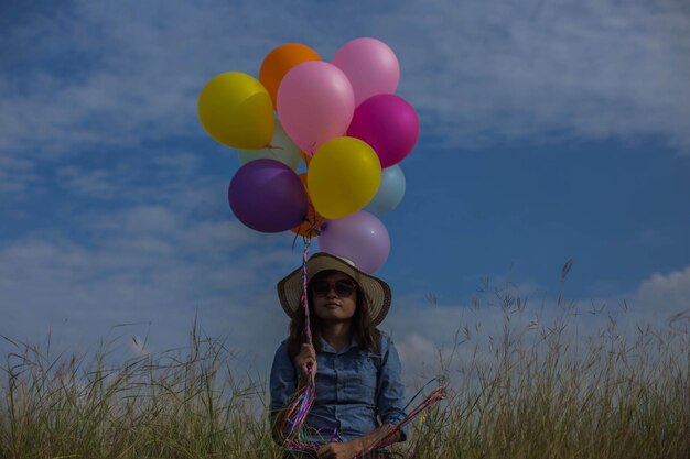 Photo woman holding balloons while sitting on field