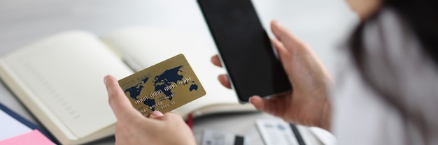 Woman holding bank credit card and phone in her hands payment of bills concept