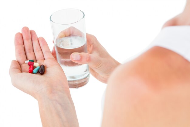 Woman holding batch of pills and glass of water