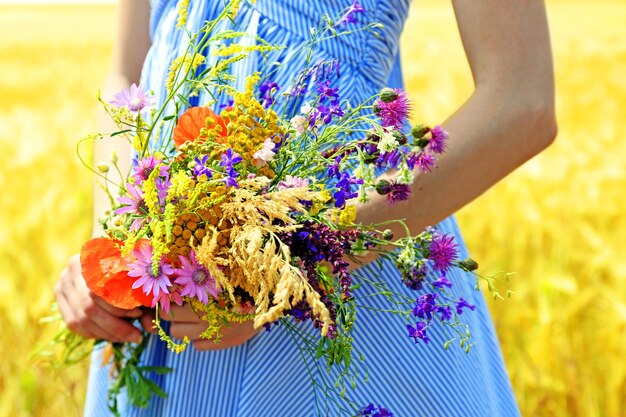 Woman holding beautiful bouquet of wildflowers outdoors