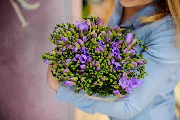 紫と緑の色調で美しい花の花束を保持している女性